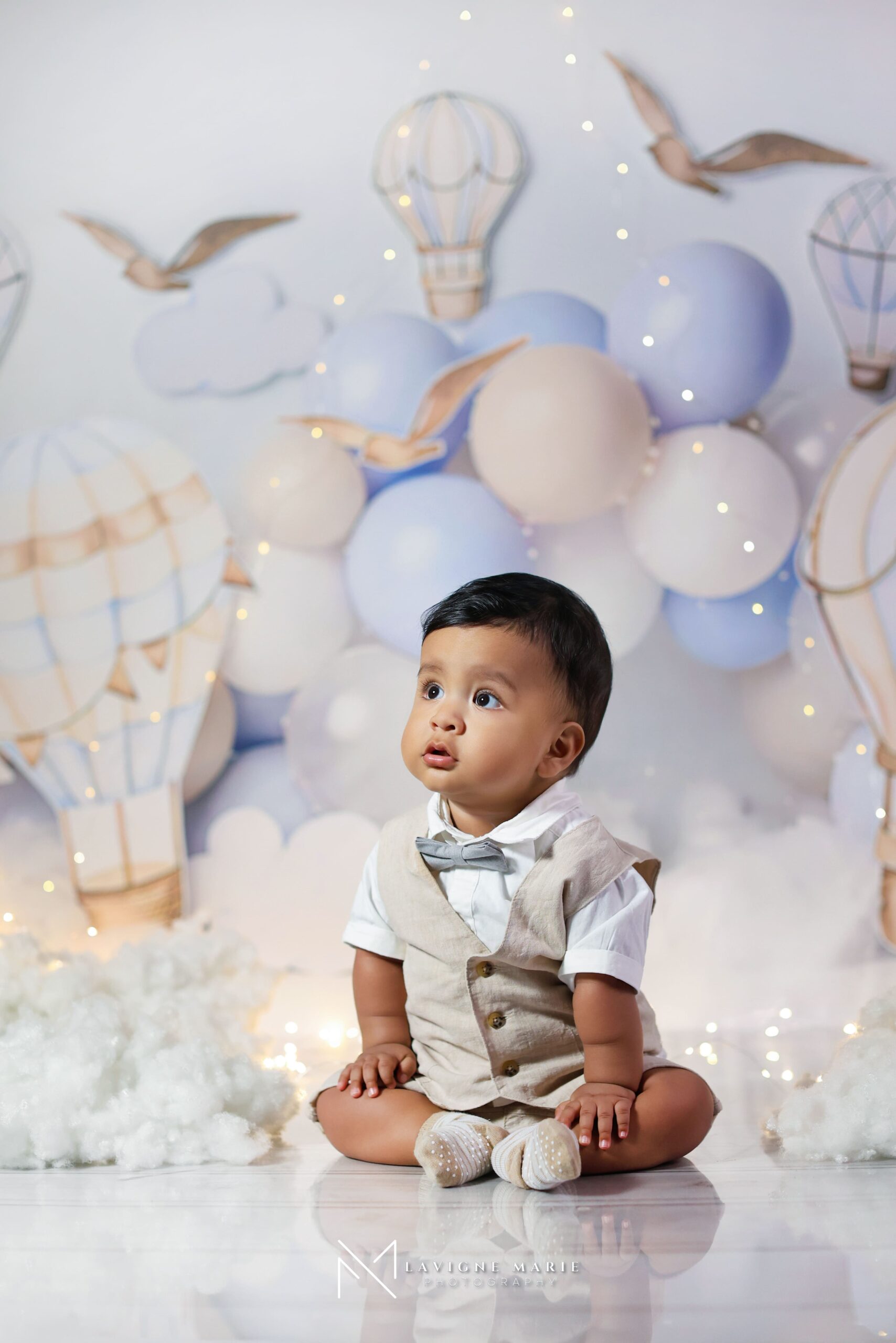 First birthday photoshoot with baby boy sitting in front of an airplane themed backdrop