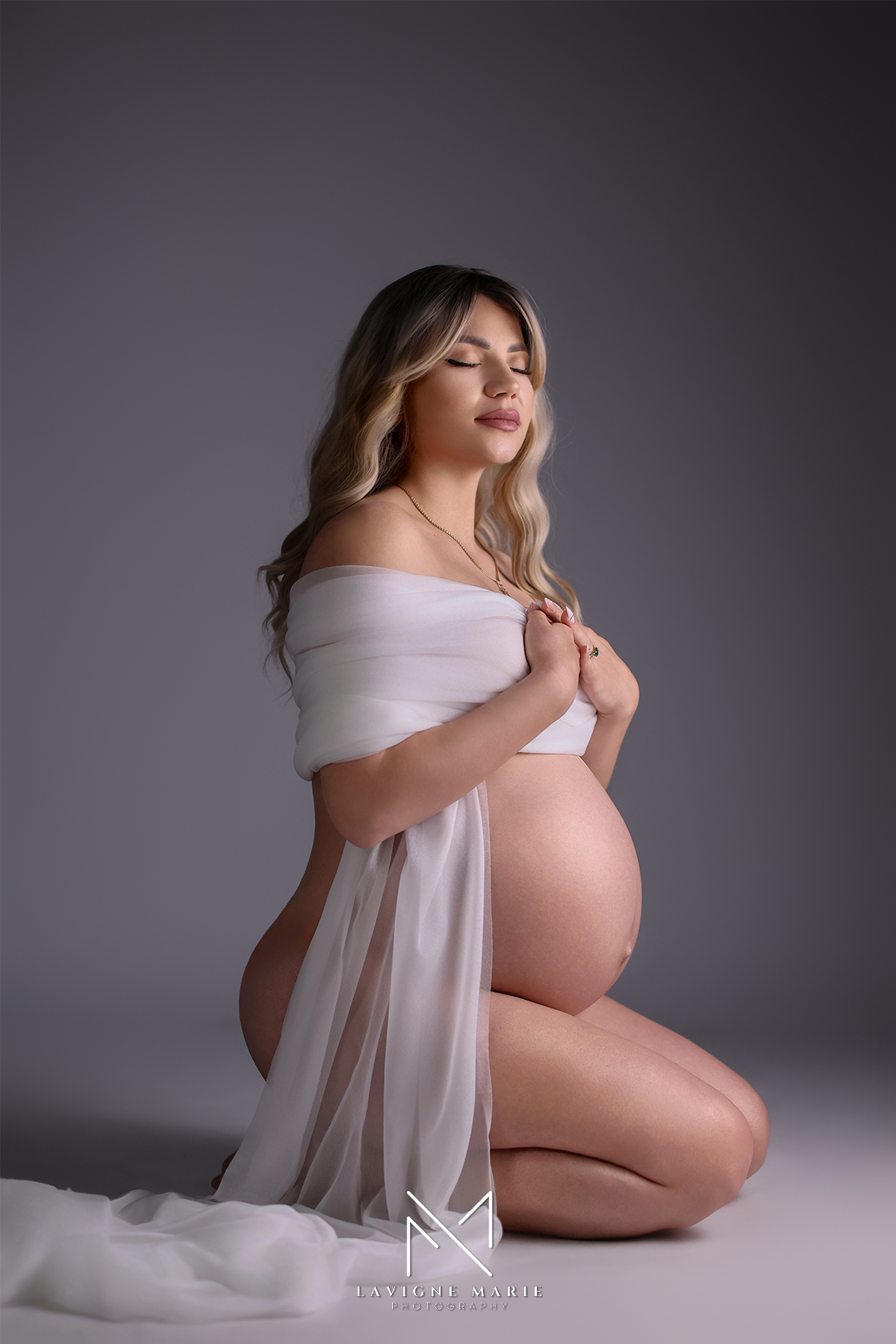 Elegant maternity boudoir studio photoshoot in London featuring a pregnant woman posing gracefully in soft lighting