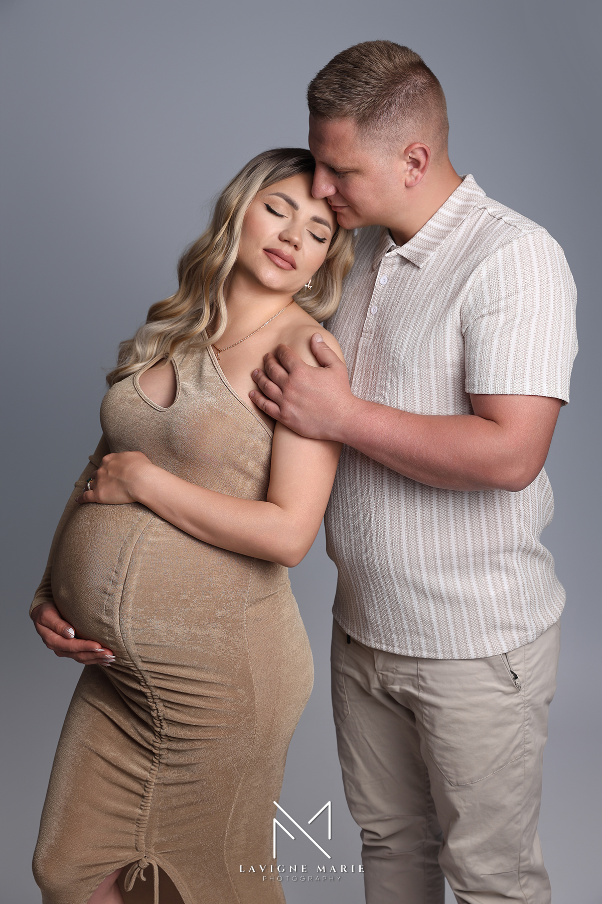 Expecting couple posing together during a maternity couple photoshoot in a professional studio in London