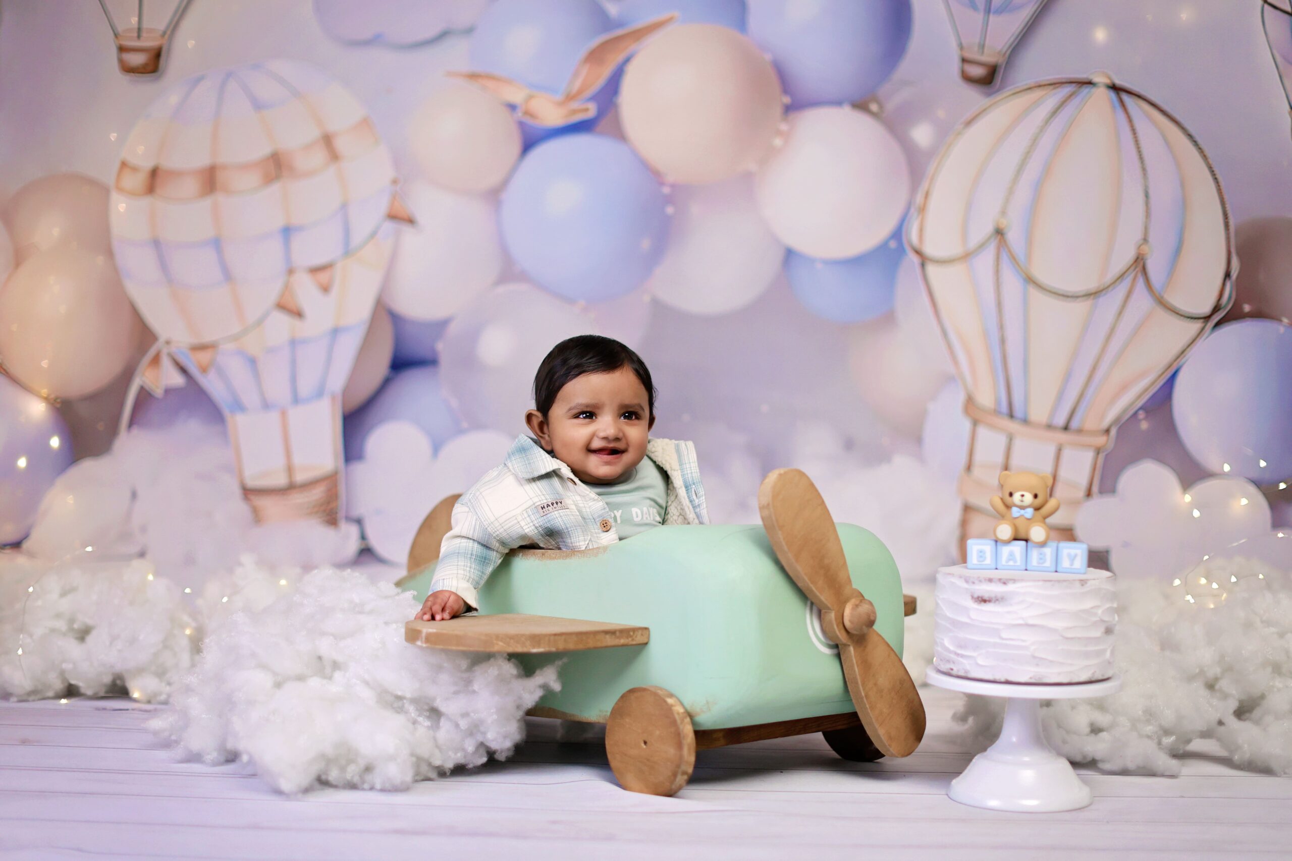 One-year-old child posing with airplane-themed props during a studio birthday photoshoot.