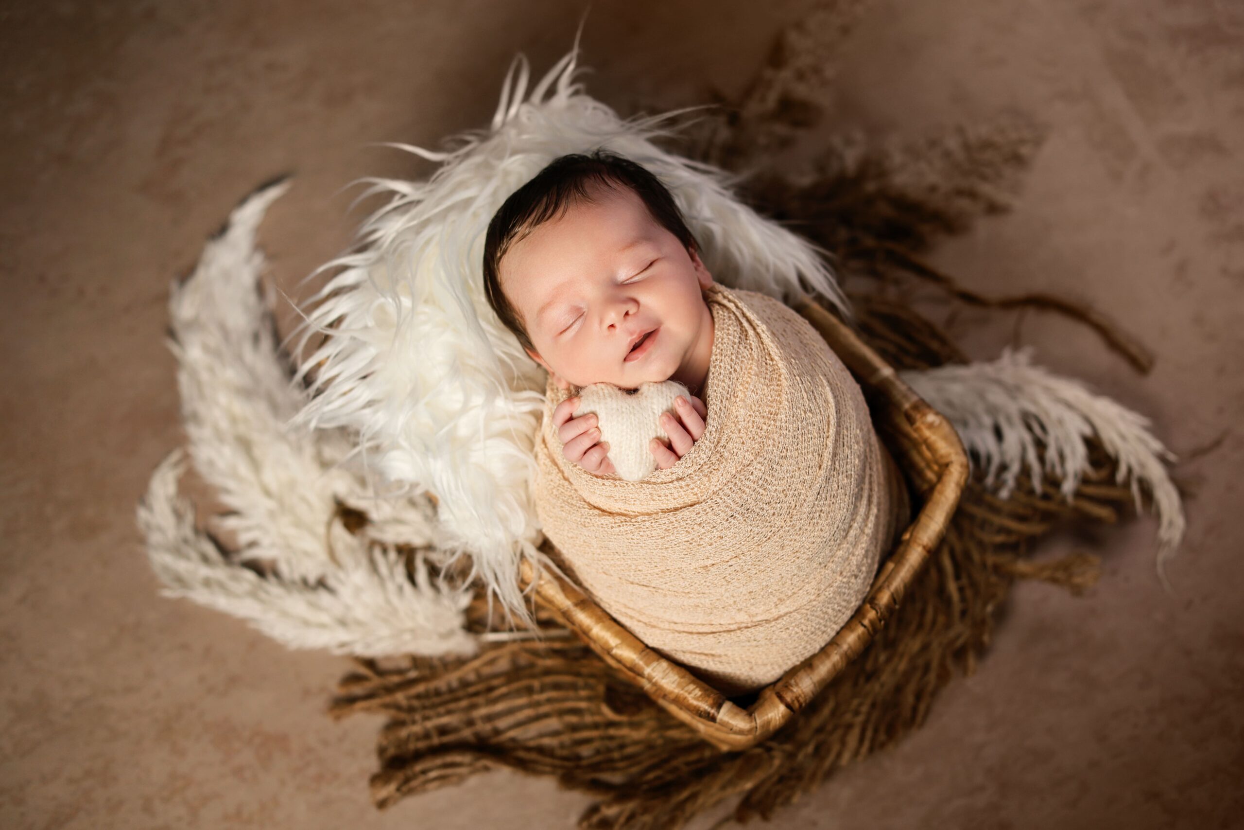 Soft and minimal studio newborn photography featuring a peacefully sleeping baby styled with neutral tones and natural textures