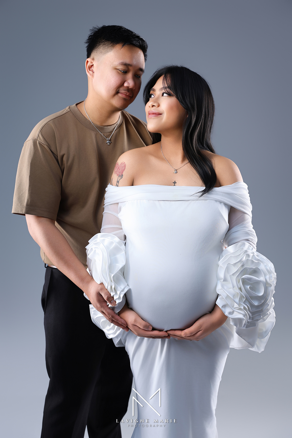 Expectant couple embracing during maternity photoshoot with family posing ideas in London studio