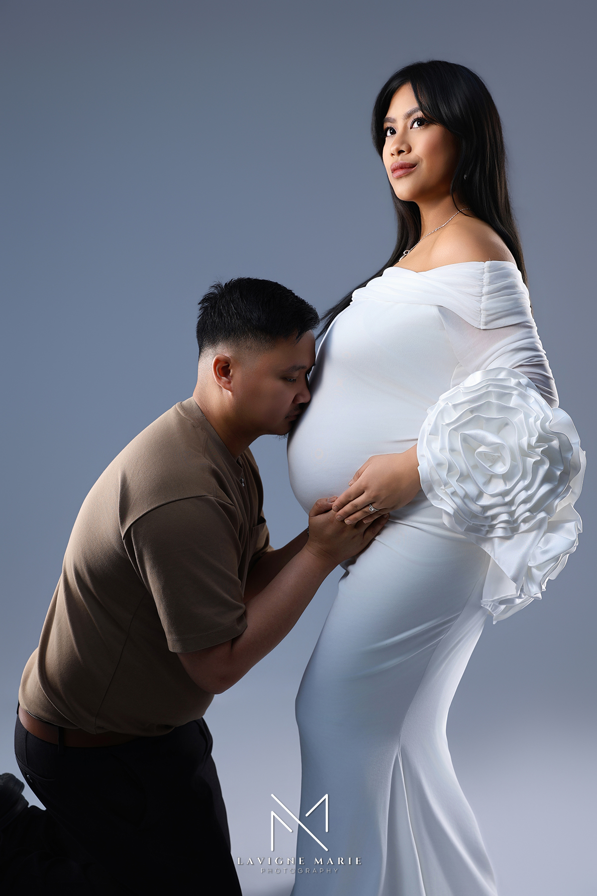 Studio maternity photoshoot with pregnant woman in fitted white dress highlighting baby bump
