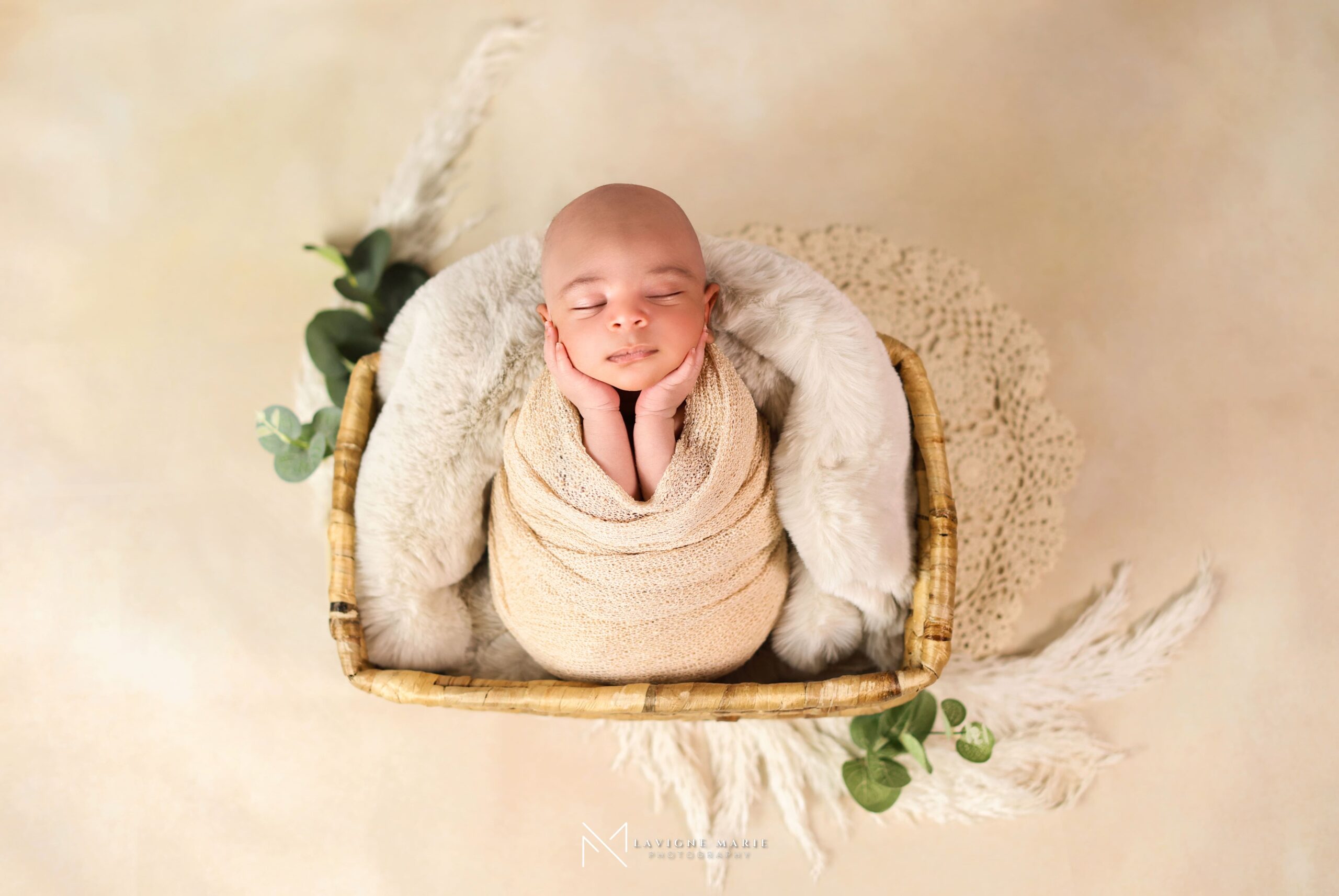Newborn baby photoshoot on a light cream backdrop with soft studio lighting and gentle posing