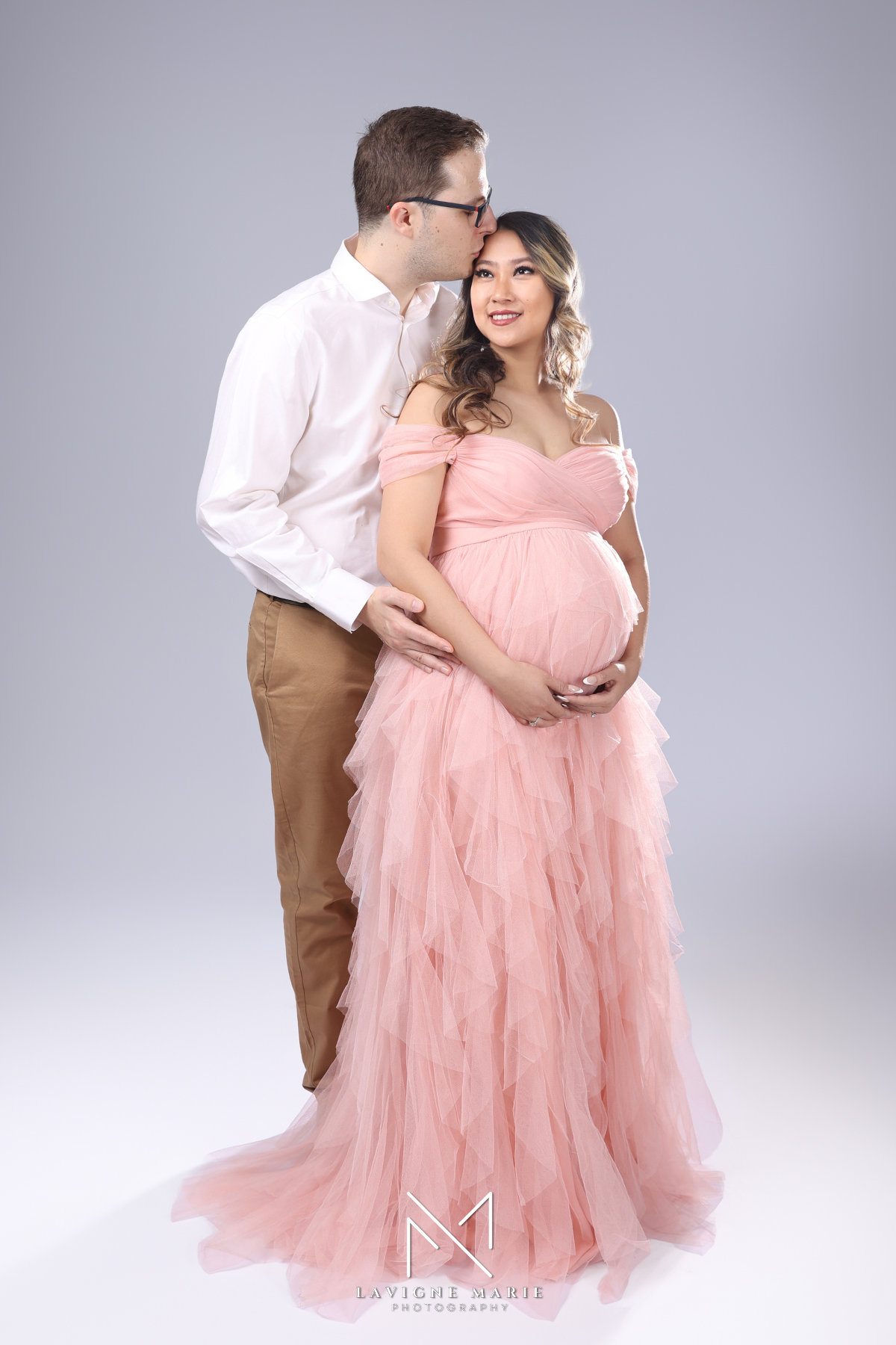 Expectant mother smiling during maternity photoshoot in London studio captured by female photographer with soft natural tones
