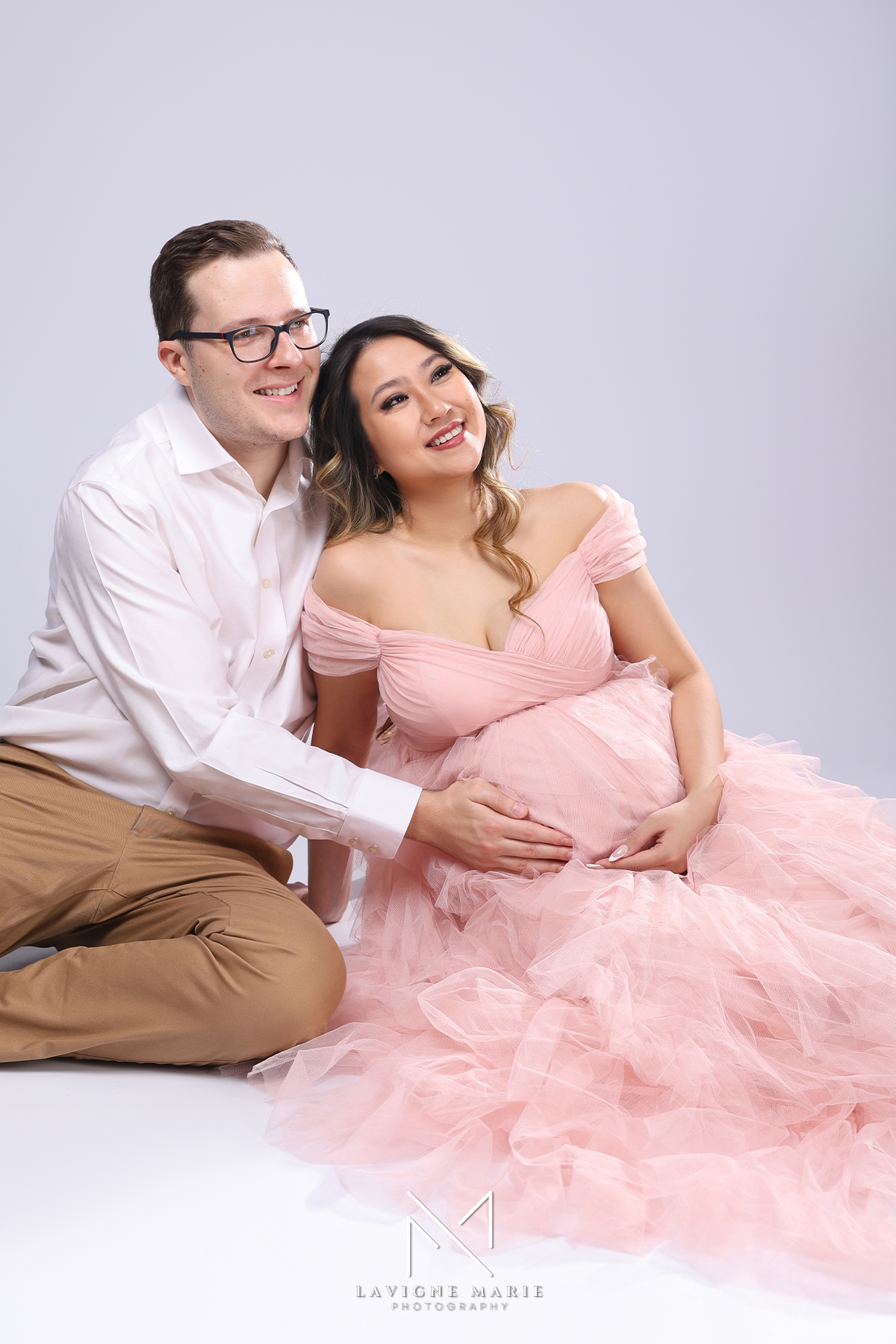 Pregnant woman posing in elegant maternity studio photoshoot captured by female photographer in London with soft lighting and neutral backdrop